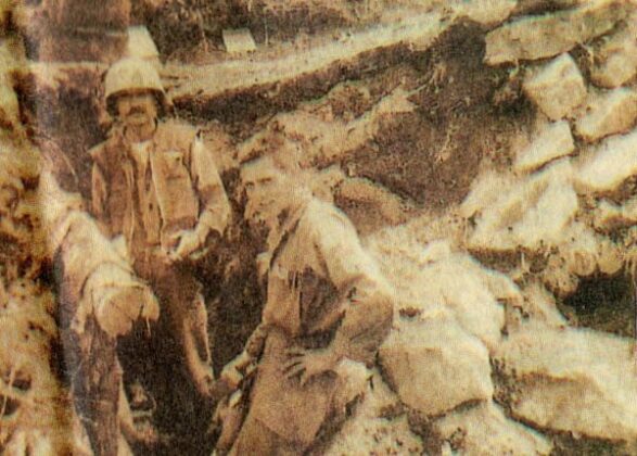 Two soldiers stand in the trench and rubble of a destroyed bunker in photo from the end of the Korean War